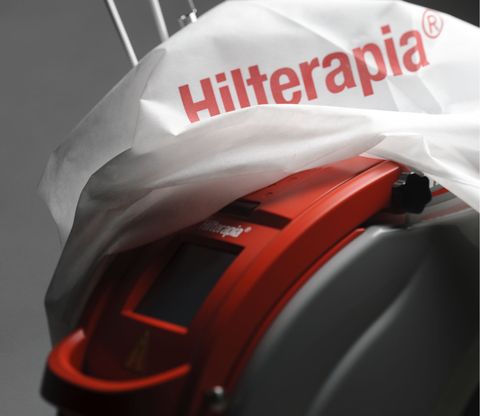Dispositivo per hiloterapia sotto una copertura bianca, che mostra un primo piano di apparecchiature mediche rosse e nere.