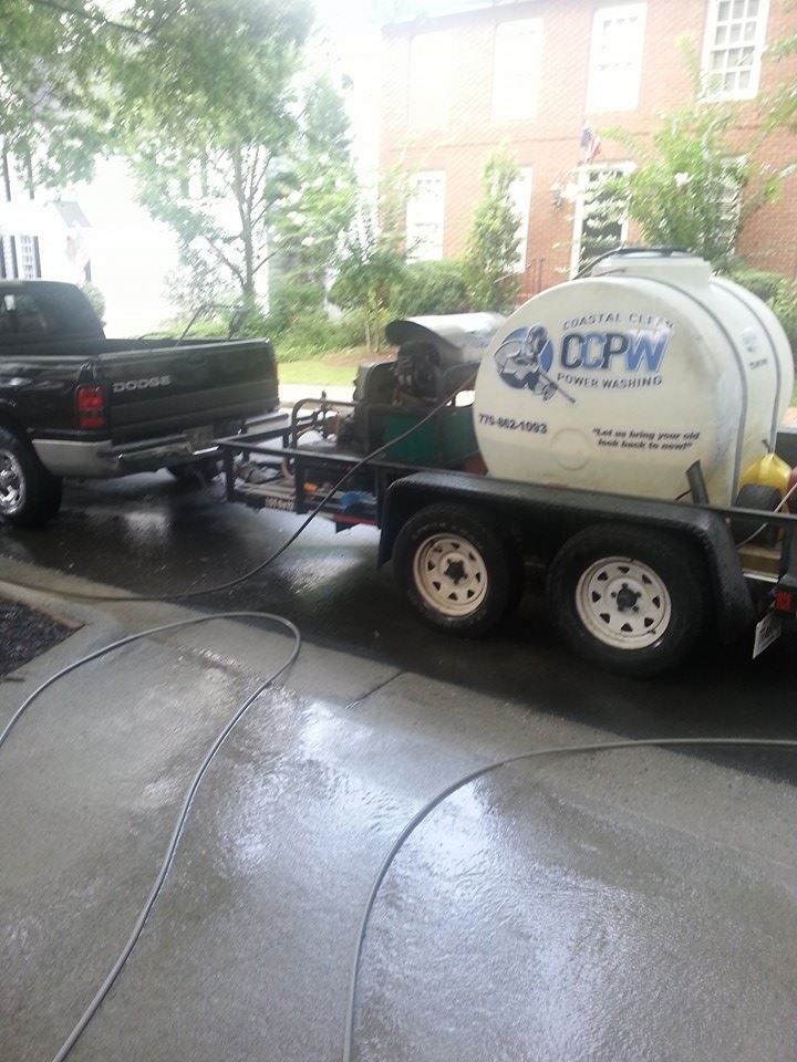 A black pickup truck towing a trailer with a white water tank marked 