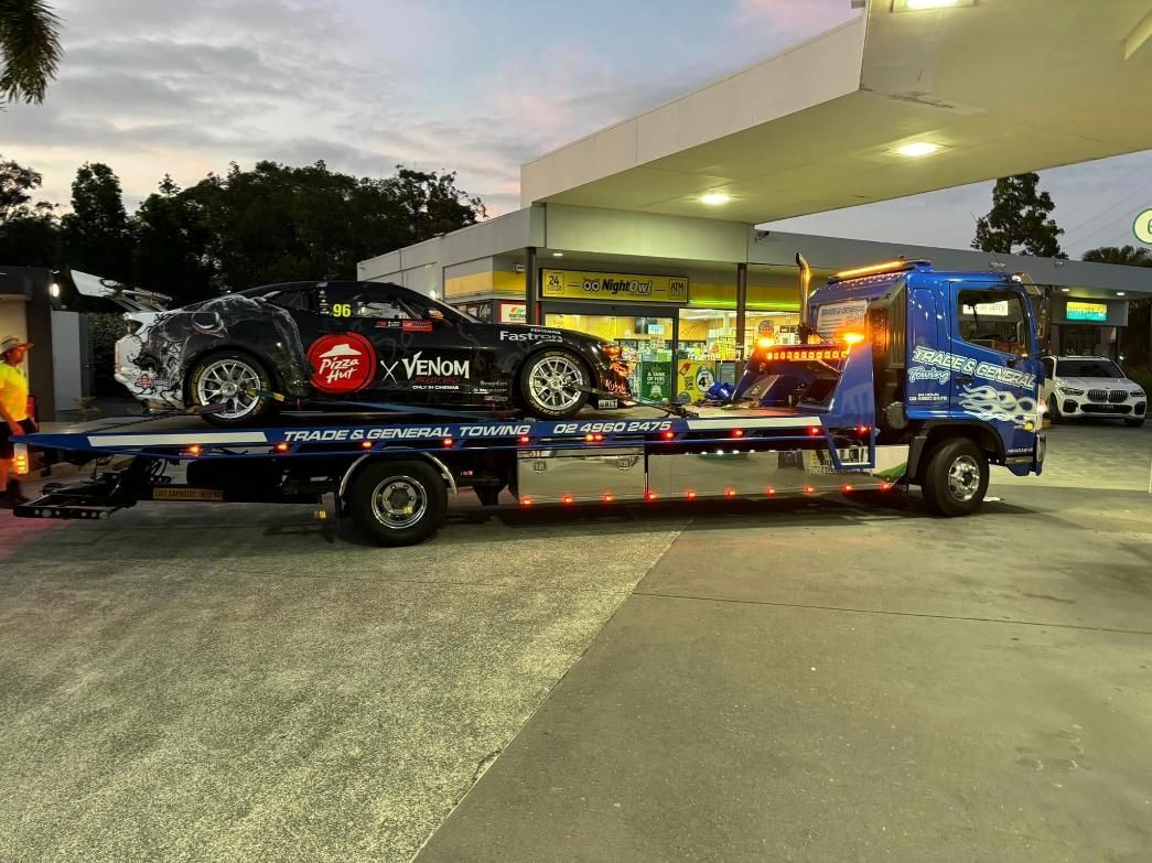 A Tow Truck is Towing a Car in a Parking Lot — Trade & General Towing in Sandgate, NSW