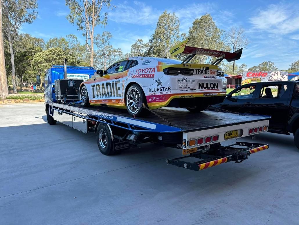 A Race Car is Being Towed by a Tow Truck — Trade & General Towing in Lake Macquarie, NSW