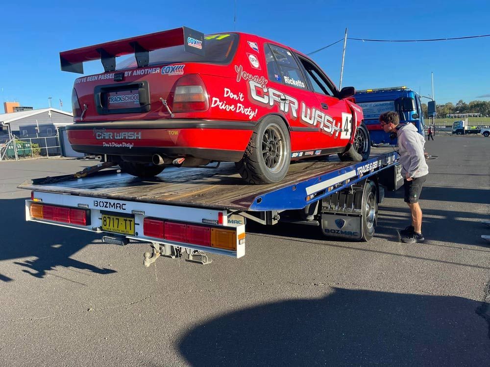 A Red Race Car is Being Towed by a Tow Truck — Trade & General Towing in Nelson Bay, NSW