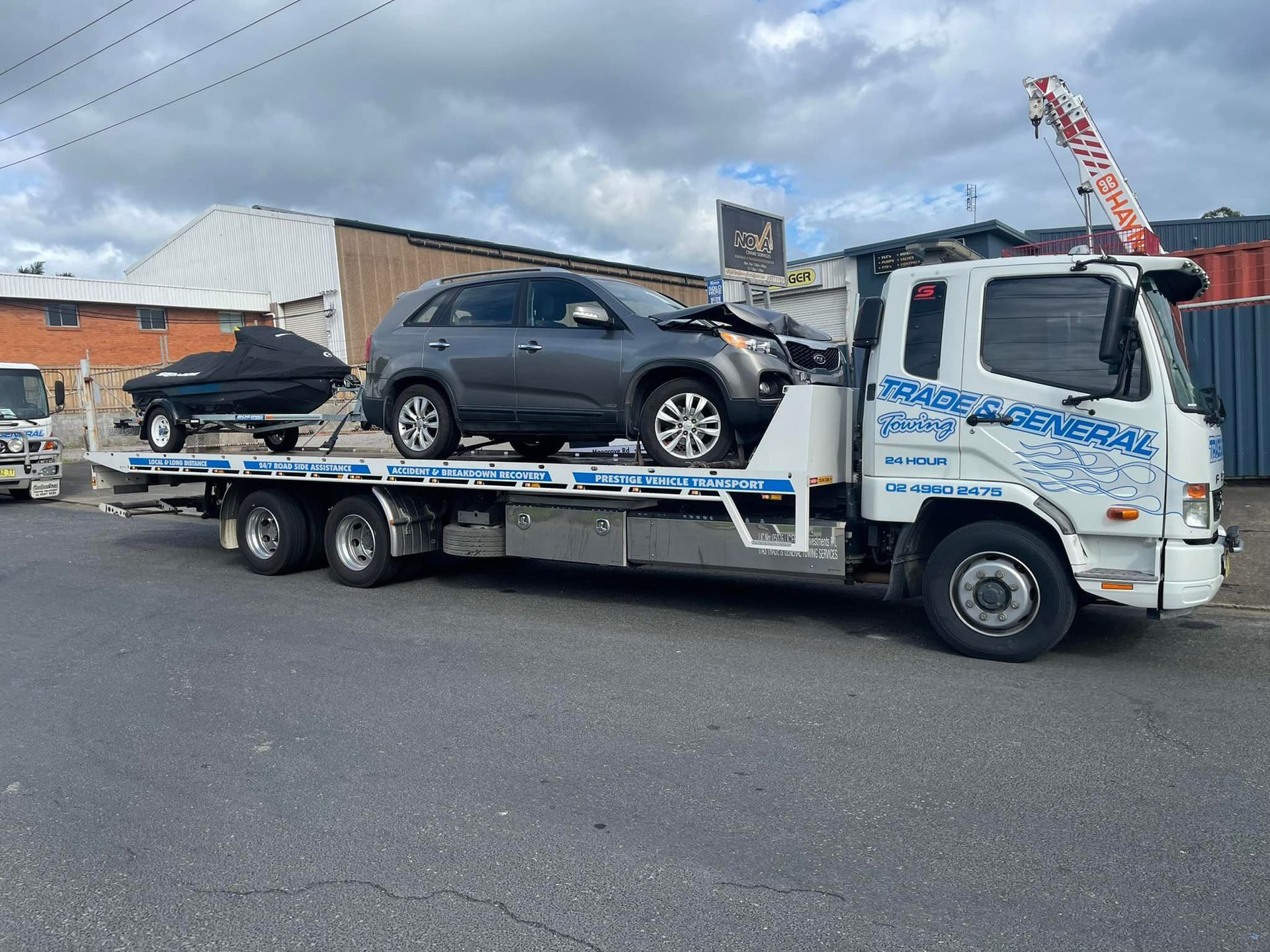 Tilt tray tow truck, carrying a Kia Sorrento and jet ski