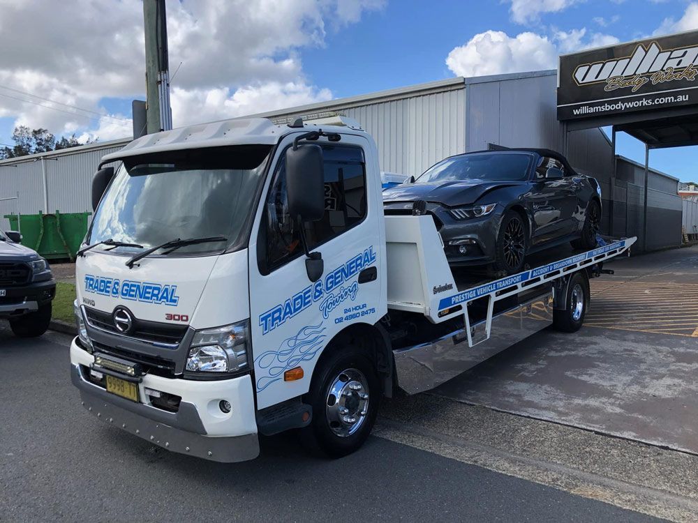 A Tow Truck With a Car on the Back is Parked on the Side of the Road — Trade & General Towing In Sandgate, NSW