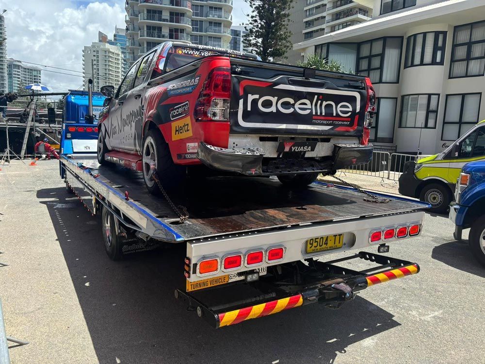 red racing car towed by truck