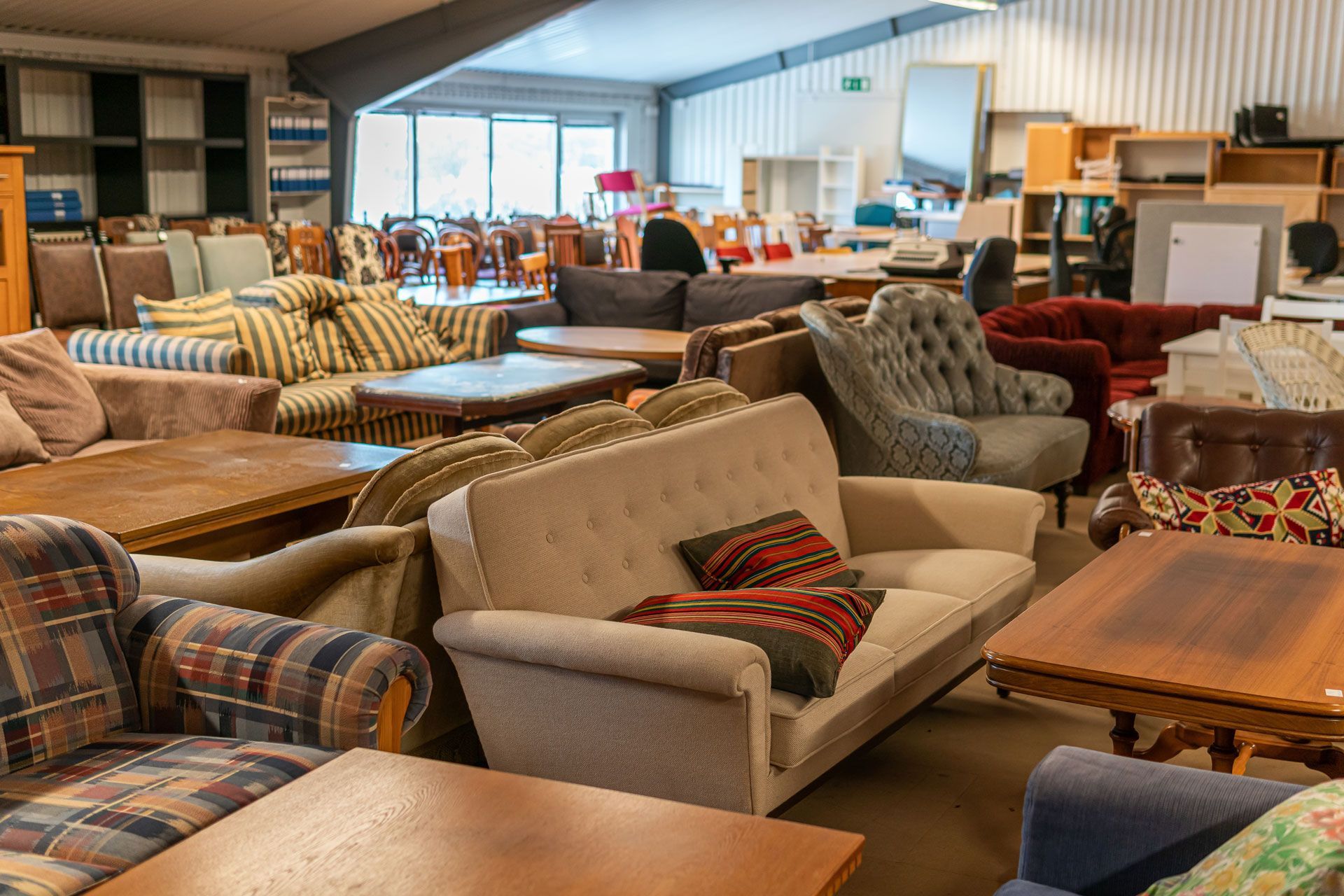 Furniture showroom with assorted sofas, armchairs, and tables in a bright display room