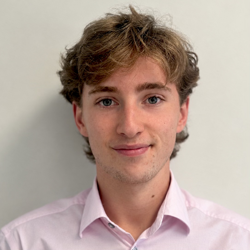 A man in a pink shirt smiling at the camera