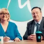 A man and a woman are sitting at a table with cups of coffee.