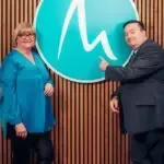 A man and a woman are standing next to each other in front of a sign.