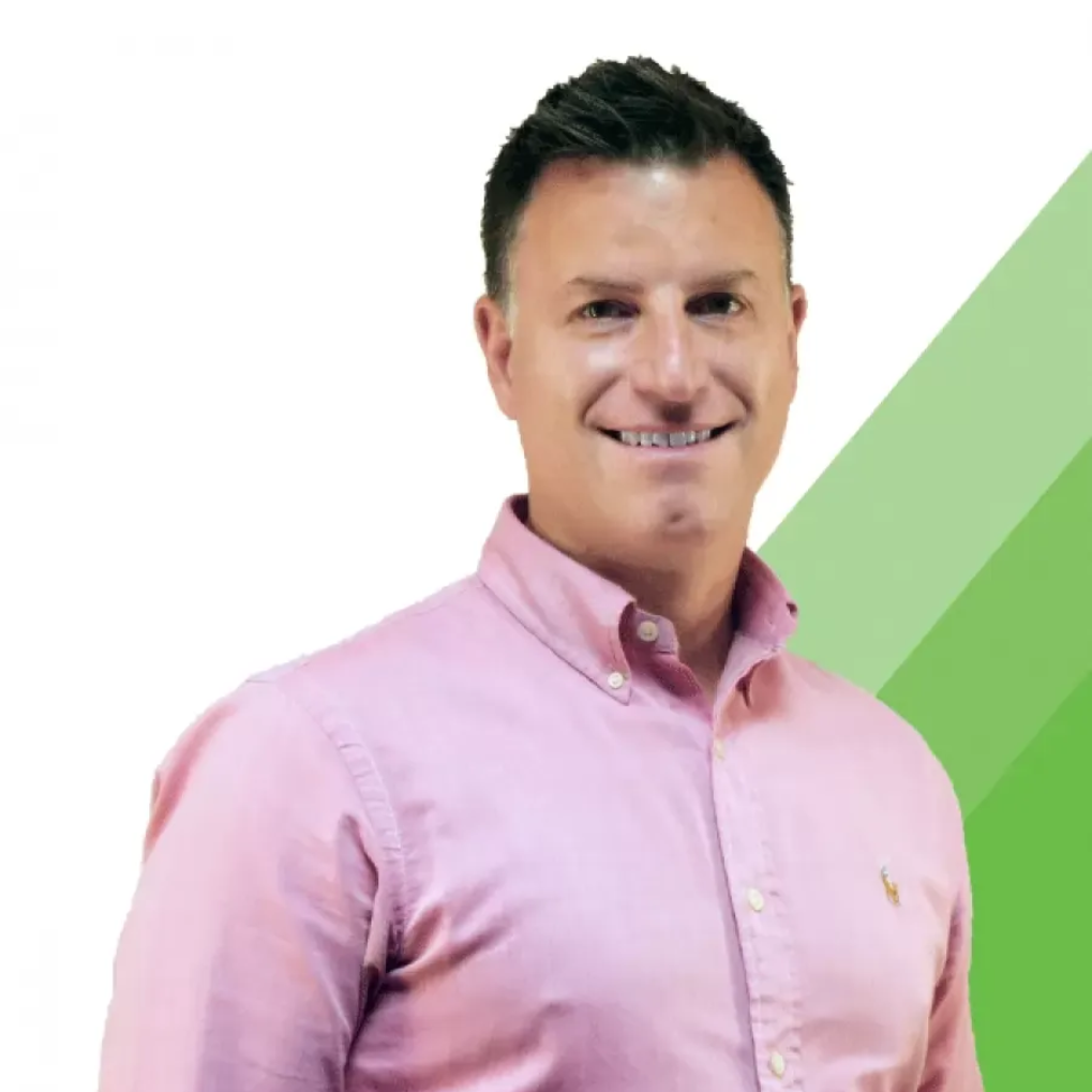 A man in a grey shirt is smiling for the camera