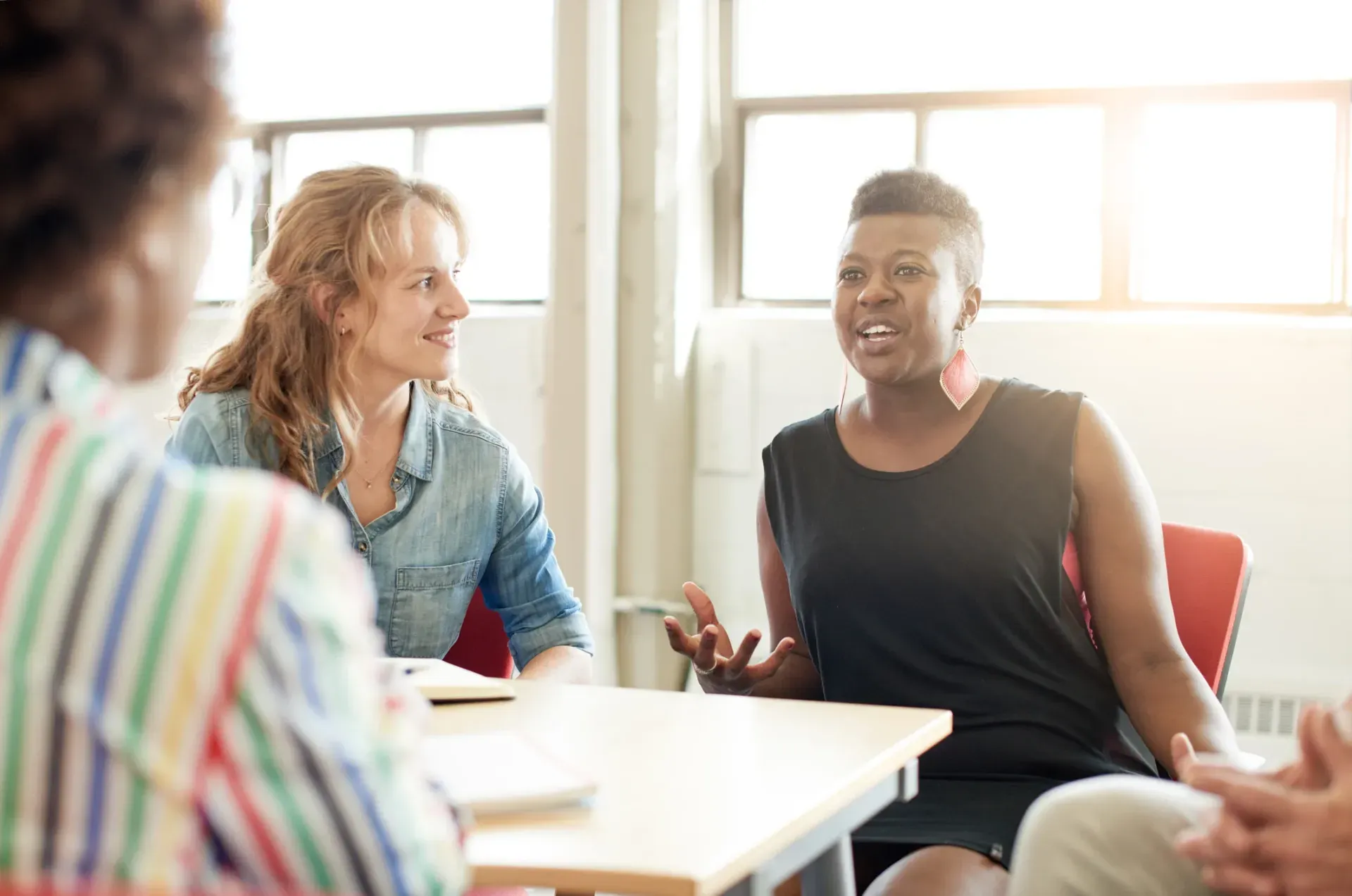 A group of people are sitting around a table having a conversation.
