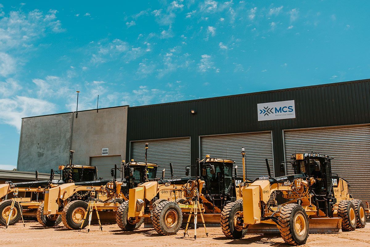 A row of construction vehicles are parked in front of a building.