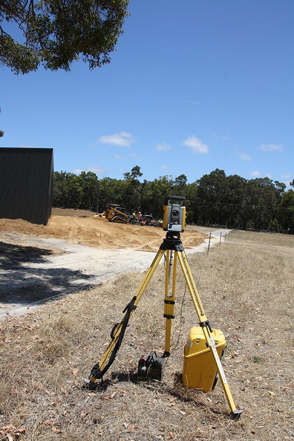 A surveyor 's equipment is sitting on a tripod in a field.