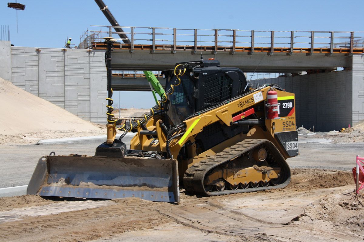 A bulldozer is working on a construction site under a bridge.