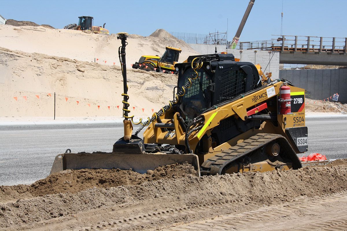 A row of construction vehicles are parked next to each other on a construction site.