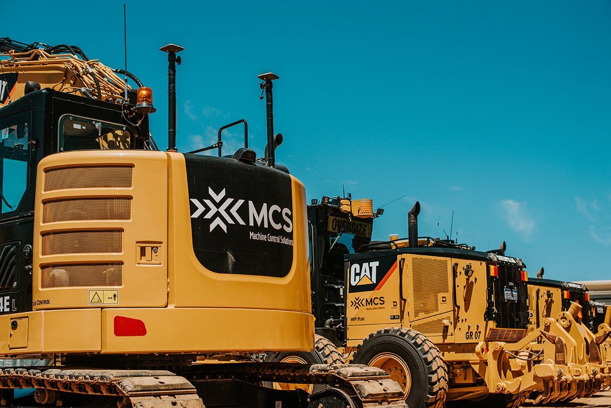 A row of construction vehicles are parked next to each other on a construction site.