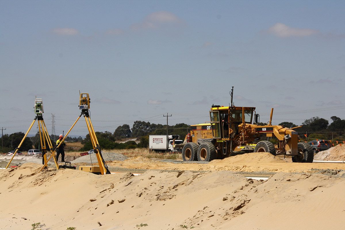 A construction site with a bulldozer and a man standing on a tripod.