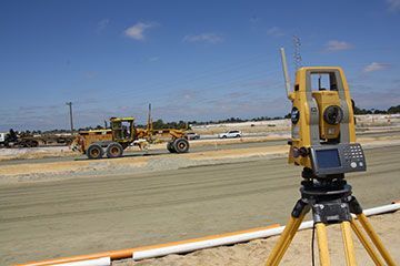 A total station is sitting on top of a tripod on a construction site.