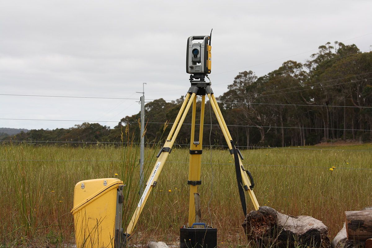 A yellow tripod with a camera on top of it in a field.