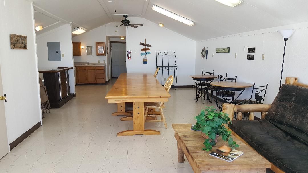 Bright open living room with long wooden table, couch, coffee table, and kitchen in back