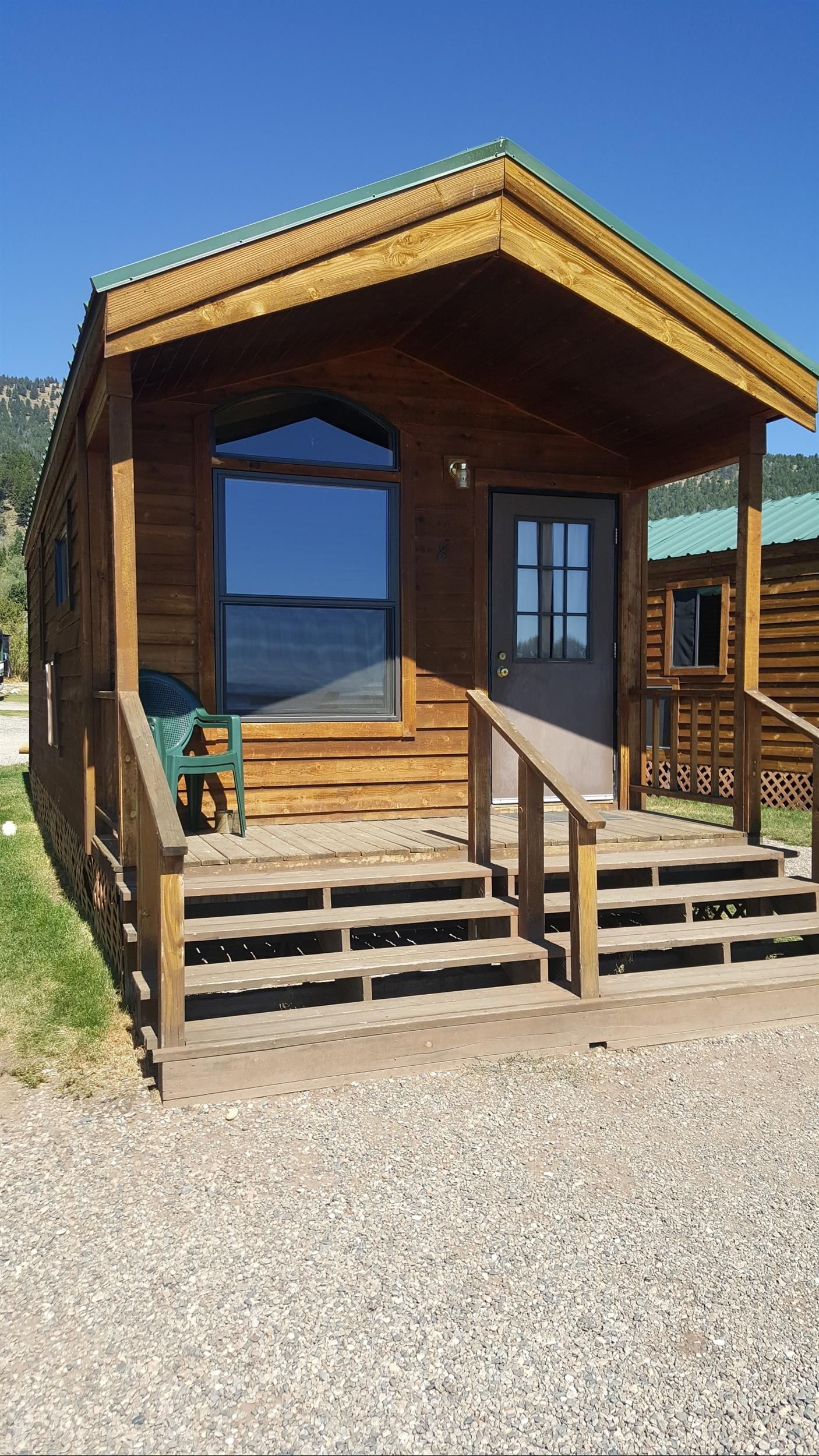 Wooden lakeside cabin porch with steps, railings, and a blue sky over the water beyond