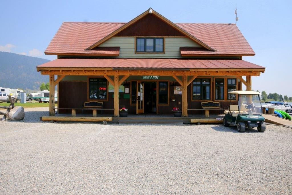 Rustic roadside lodge with a red roof and gravel parking lot, front view in daylight