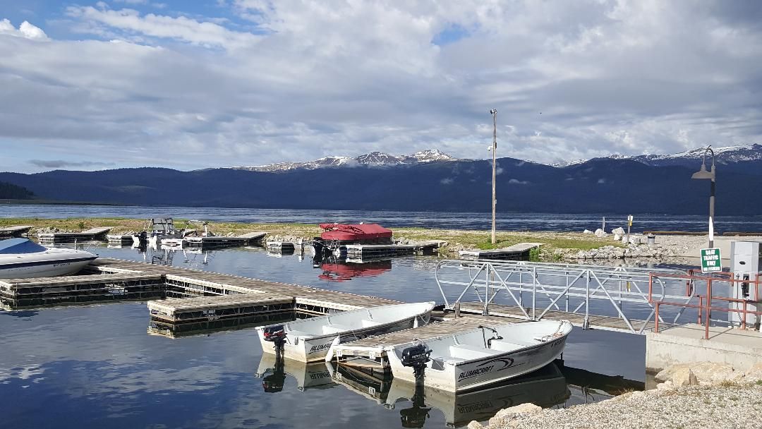 Small boats on a calm harbor with snow-capped mountains in the background
