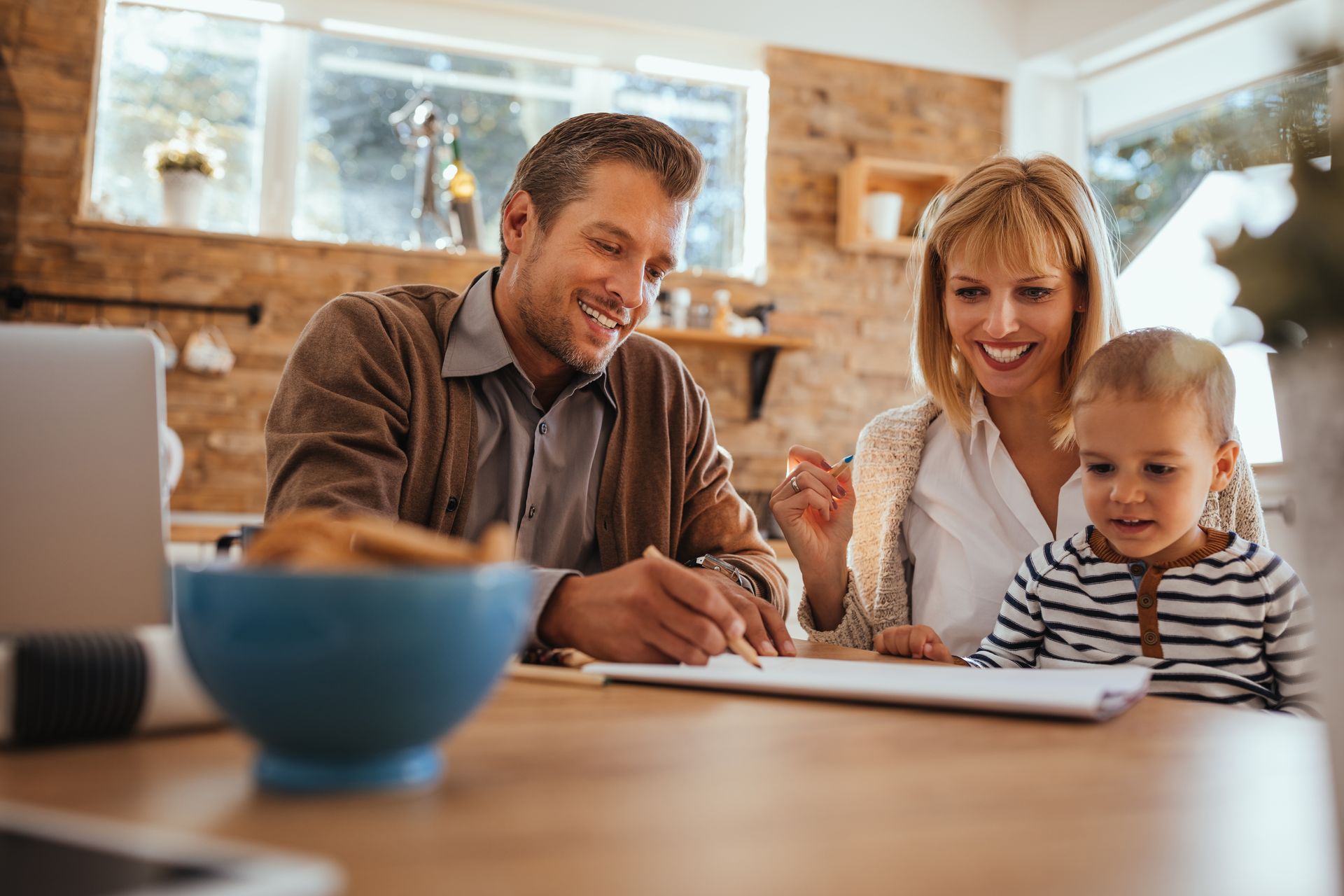 Family reviewing a document at a table in a warm living room.