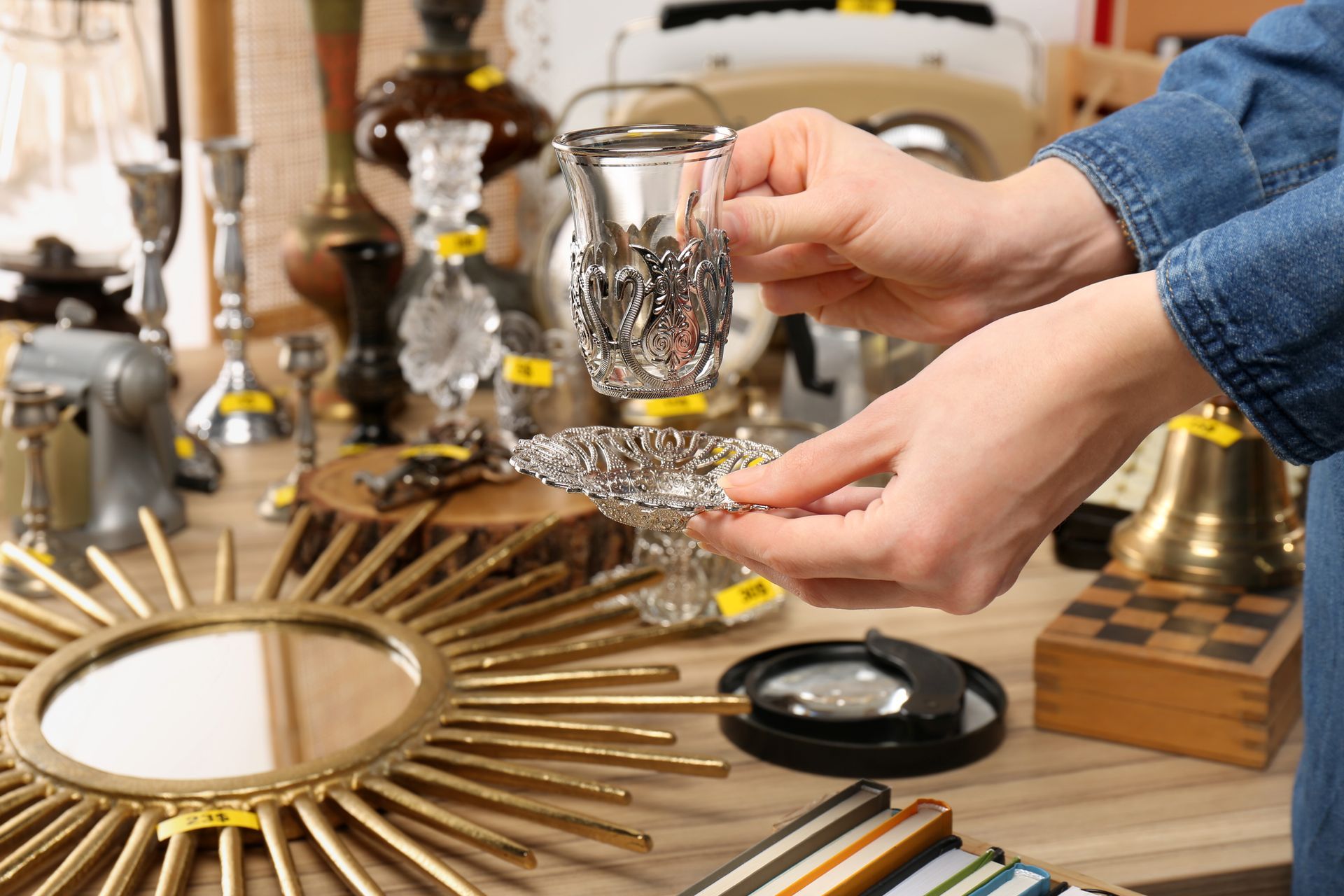 Hands arranging ornate glass and gold decor pieces on a wooden table.