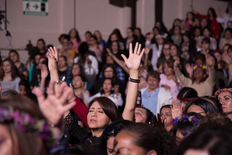 a crowd of people are raising their hands in the air .
