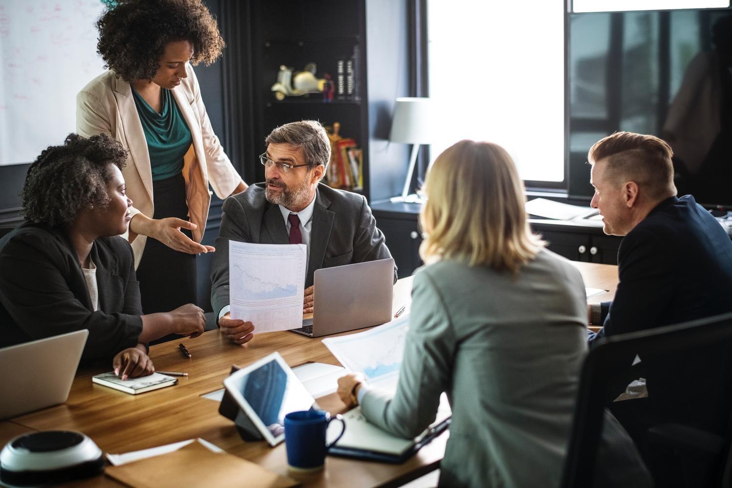 a group of people are sitting around a table having a meeting .