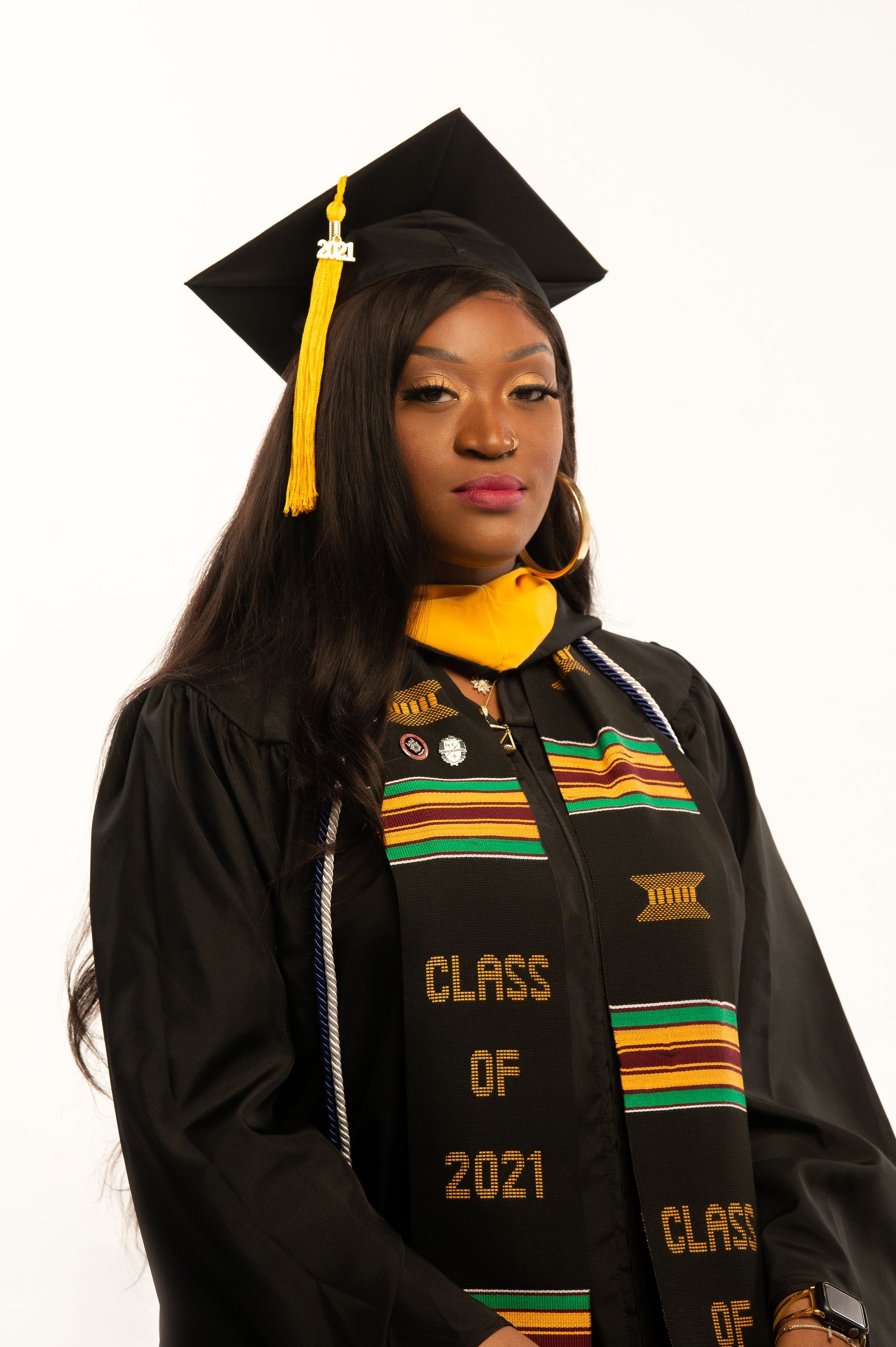 Person in graduation cap and gown with a yellow tassel and sash that says