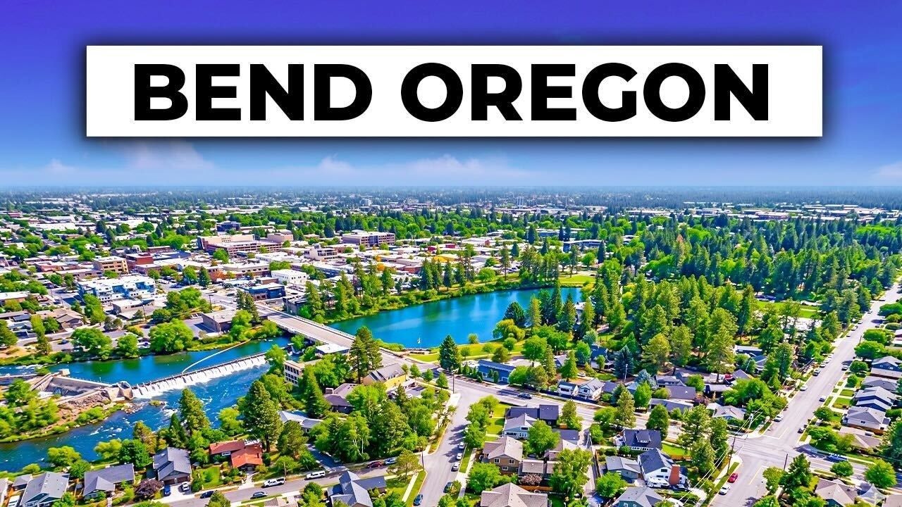 Aerial view of Bend, Oregon with a river, trees, and neighborhoods under a bright sky