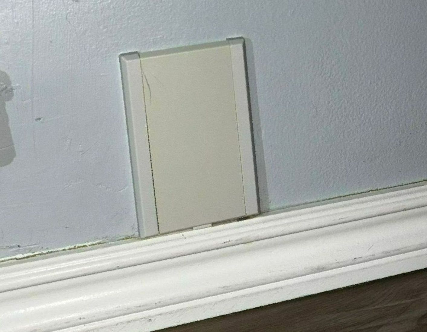 A white electrical outlet on a wall next to a white molding