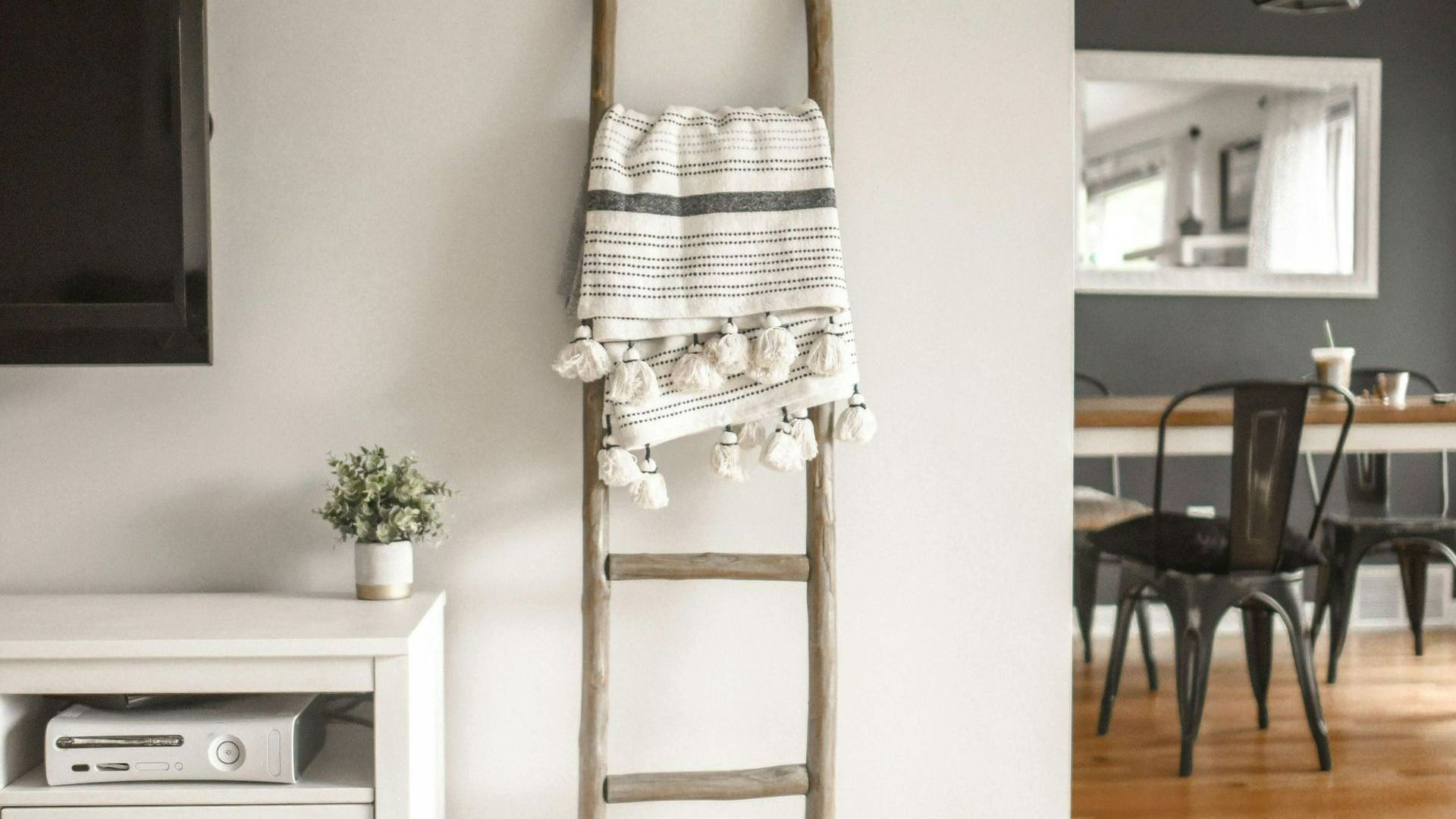 A wooden ladder with a blanket hanging from it in a living room.