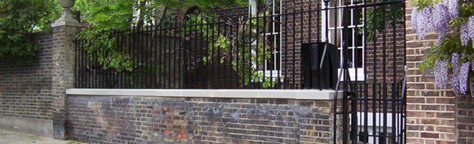 Iron fence on top of a stone wall outside a house