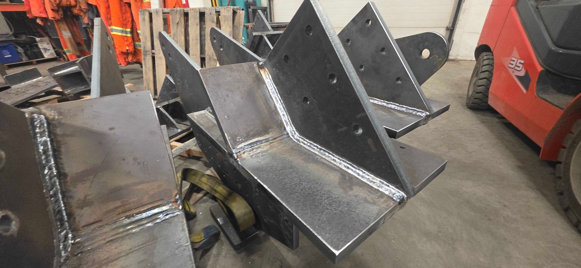 Éléments de structure en acier industriel avec joints soudés et trous de boulons, disposés dans un atelier.