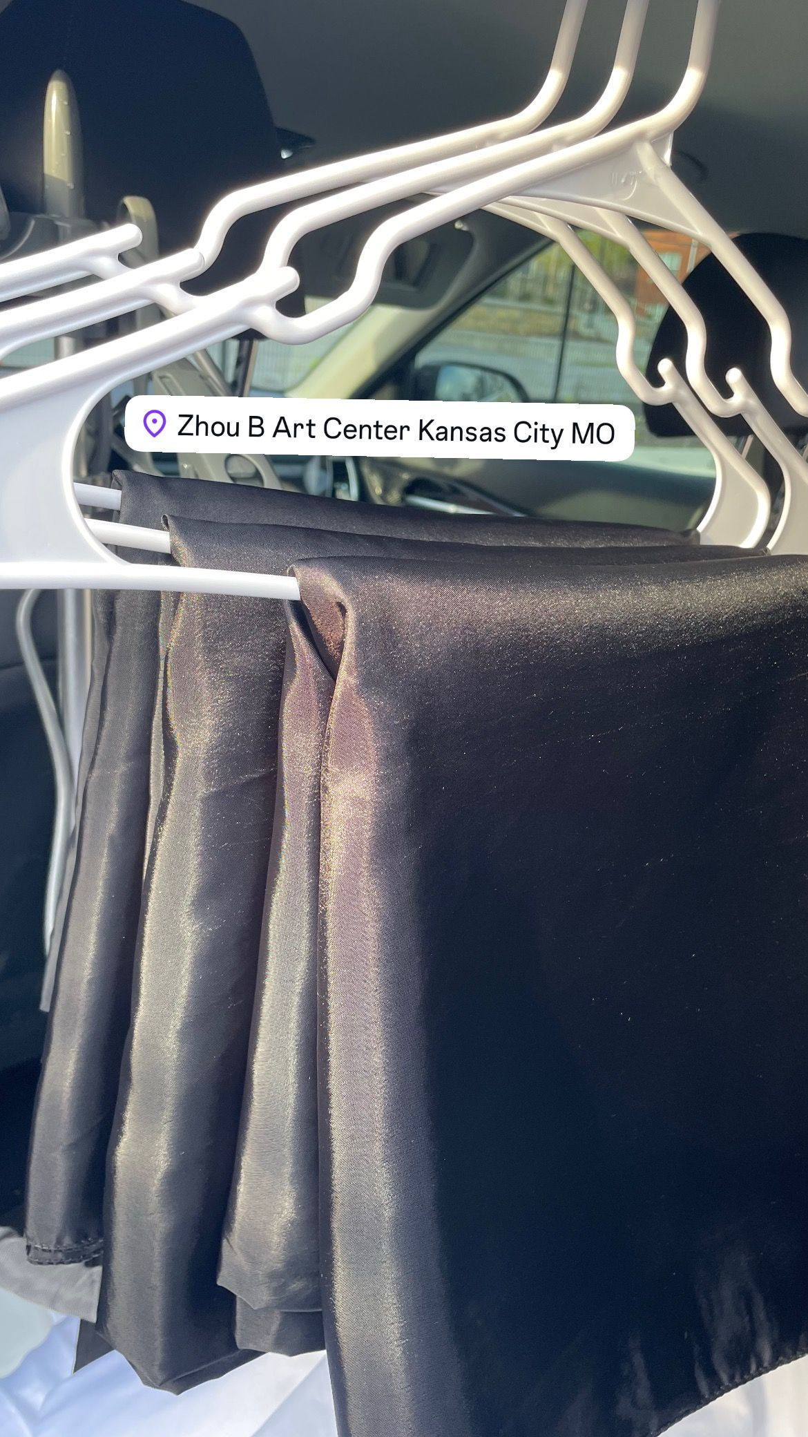 Black shiny fabric hanging on white hangers.