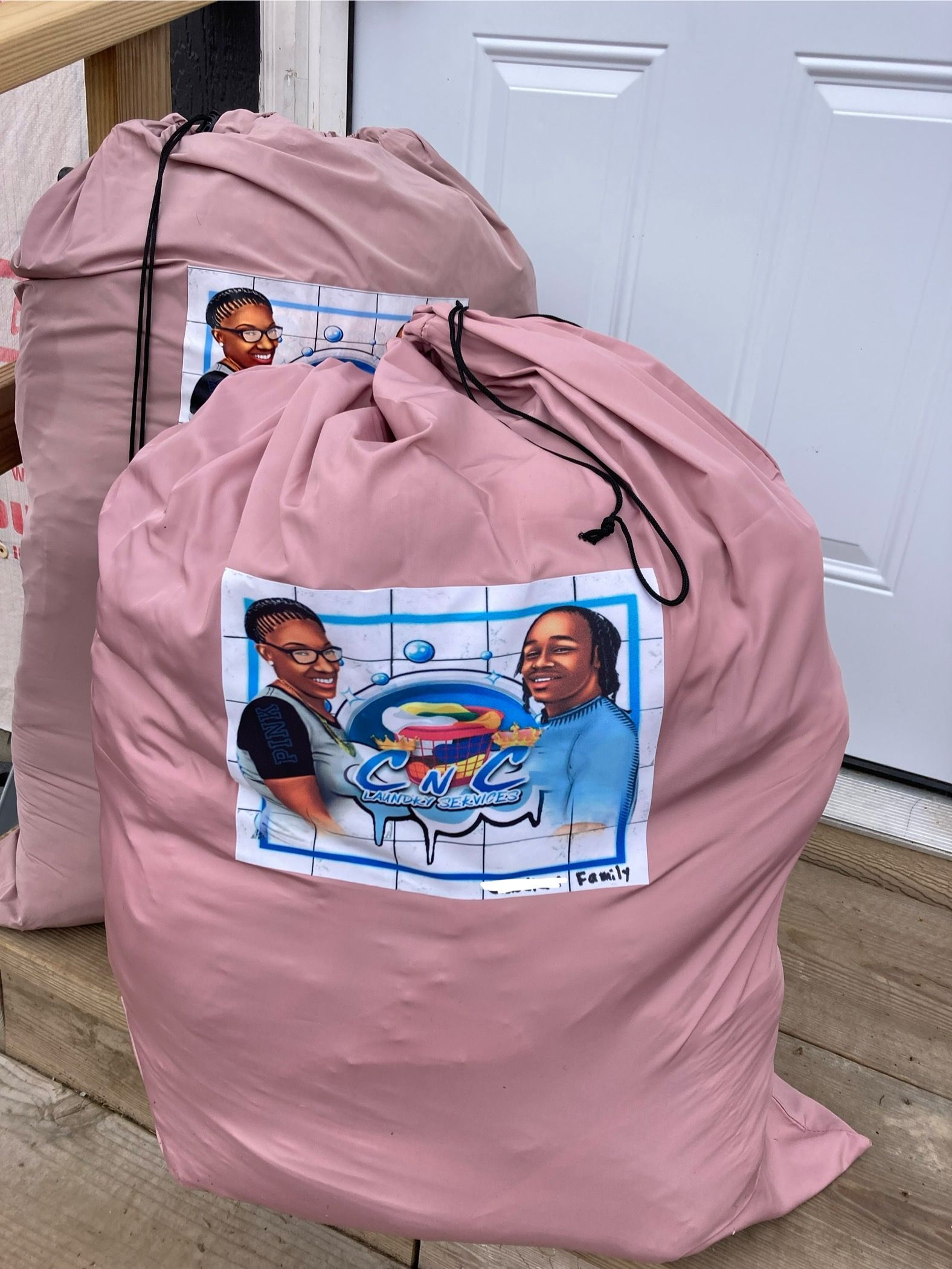 Two pink laundry bags with a label featuring women, outdoors.
