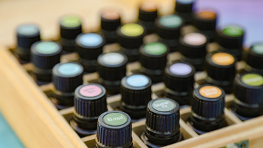 Rows of colorful essential oil bottles in a wooden tray, viewed from above