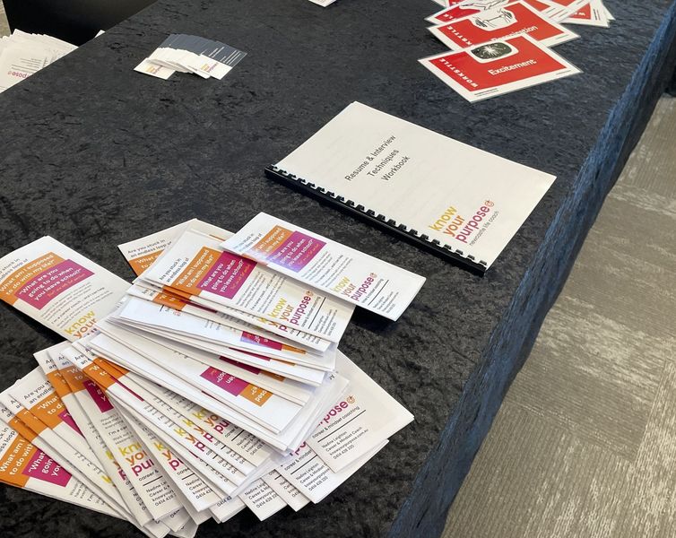 Table with event materials, including brochures, a notebook, and red-themed cards.
