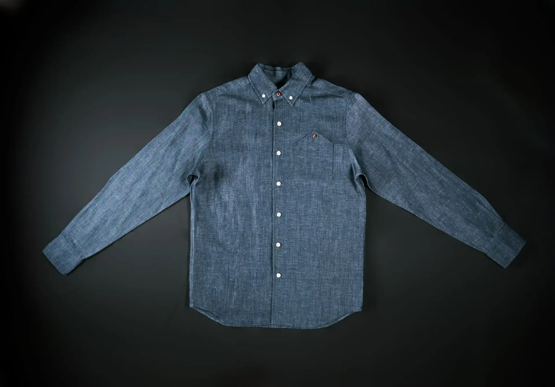 A blue shirt is laying on a black surface.