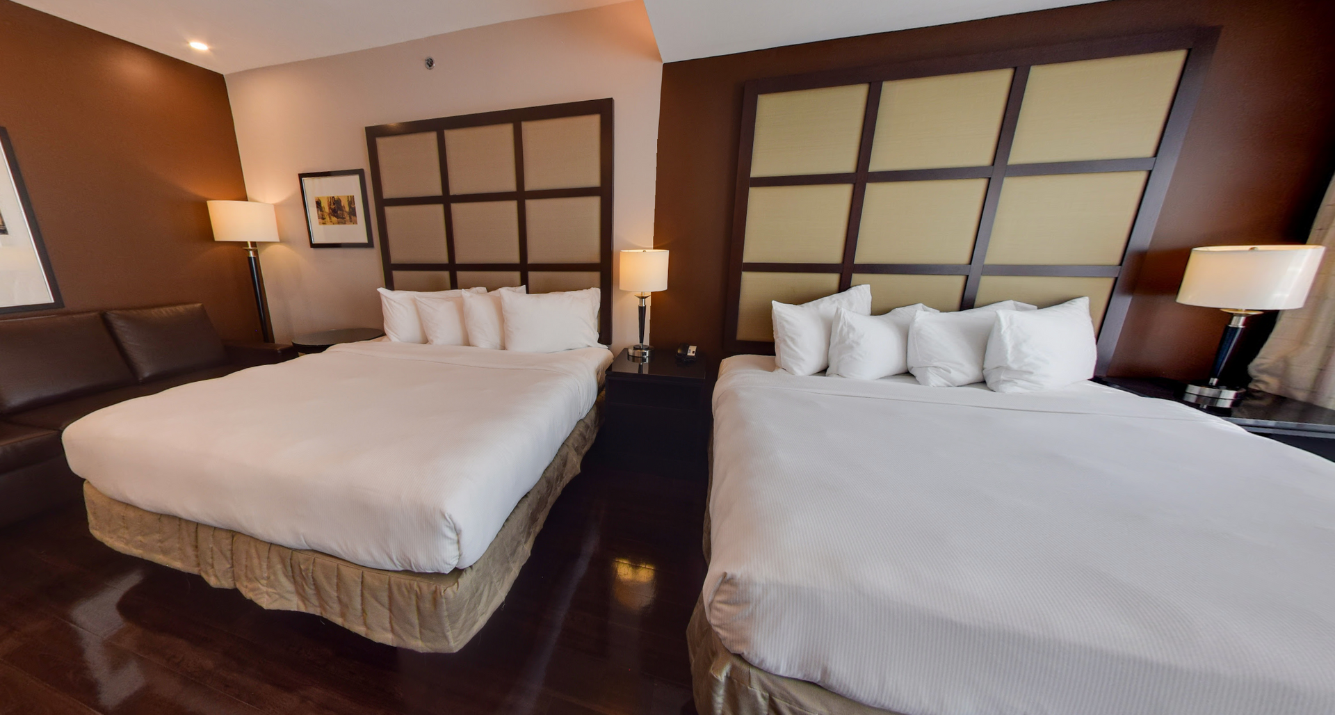 Deux lits dans une chambre d'hôtel avec des têtes de lit et des lampes marron.
