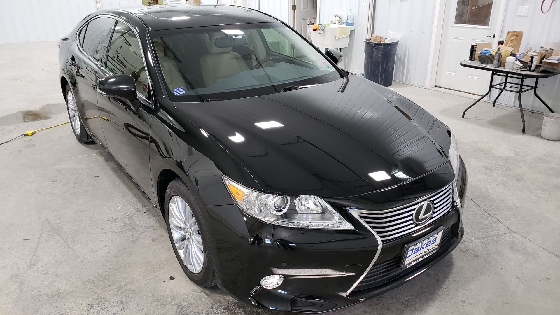 Black Lexus sedan parked in a garage, front three-quarter view.