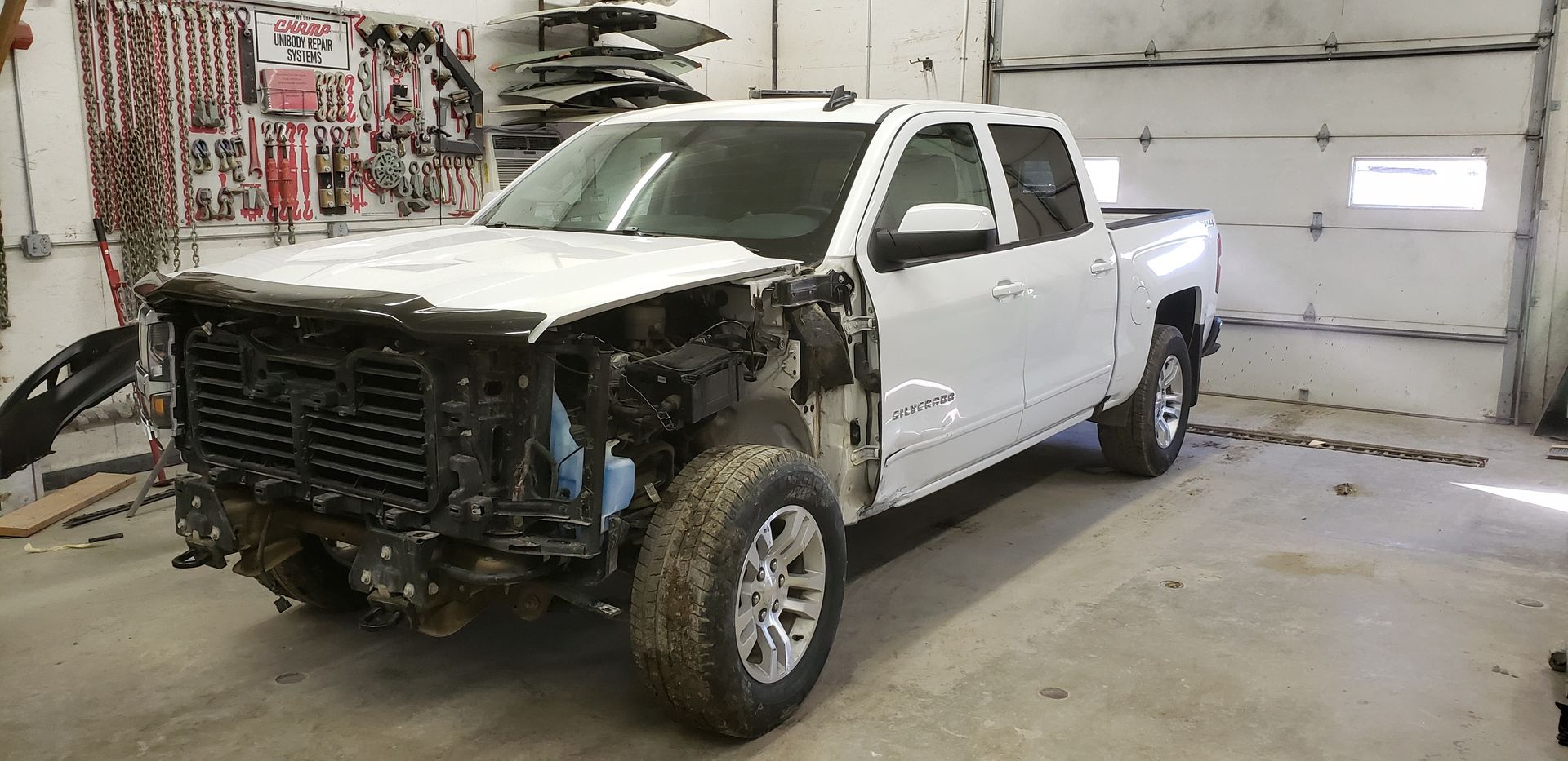 White pickup truck with front end removed in a garage workshop