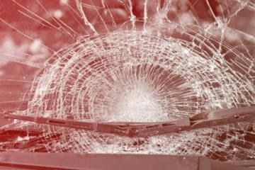 Shattered car windshield with a large impact crack and spiderweb cracks across the glass