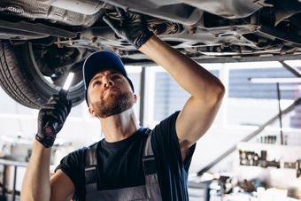 A man is working under a car in a garage.