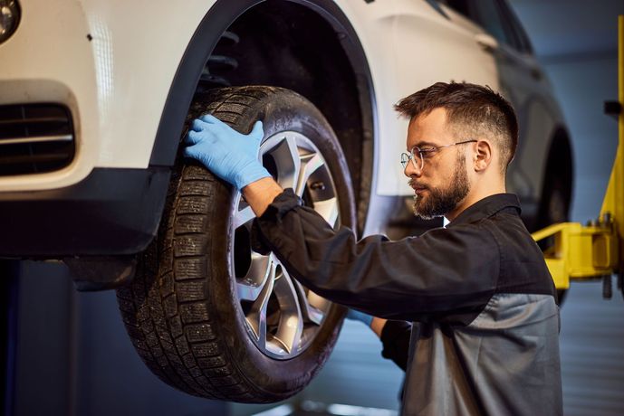 A man is changing a tire on a car in a garage.