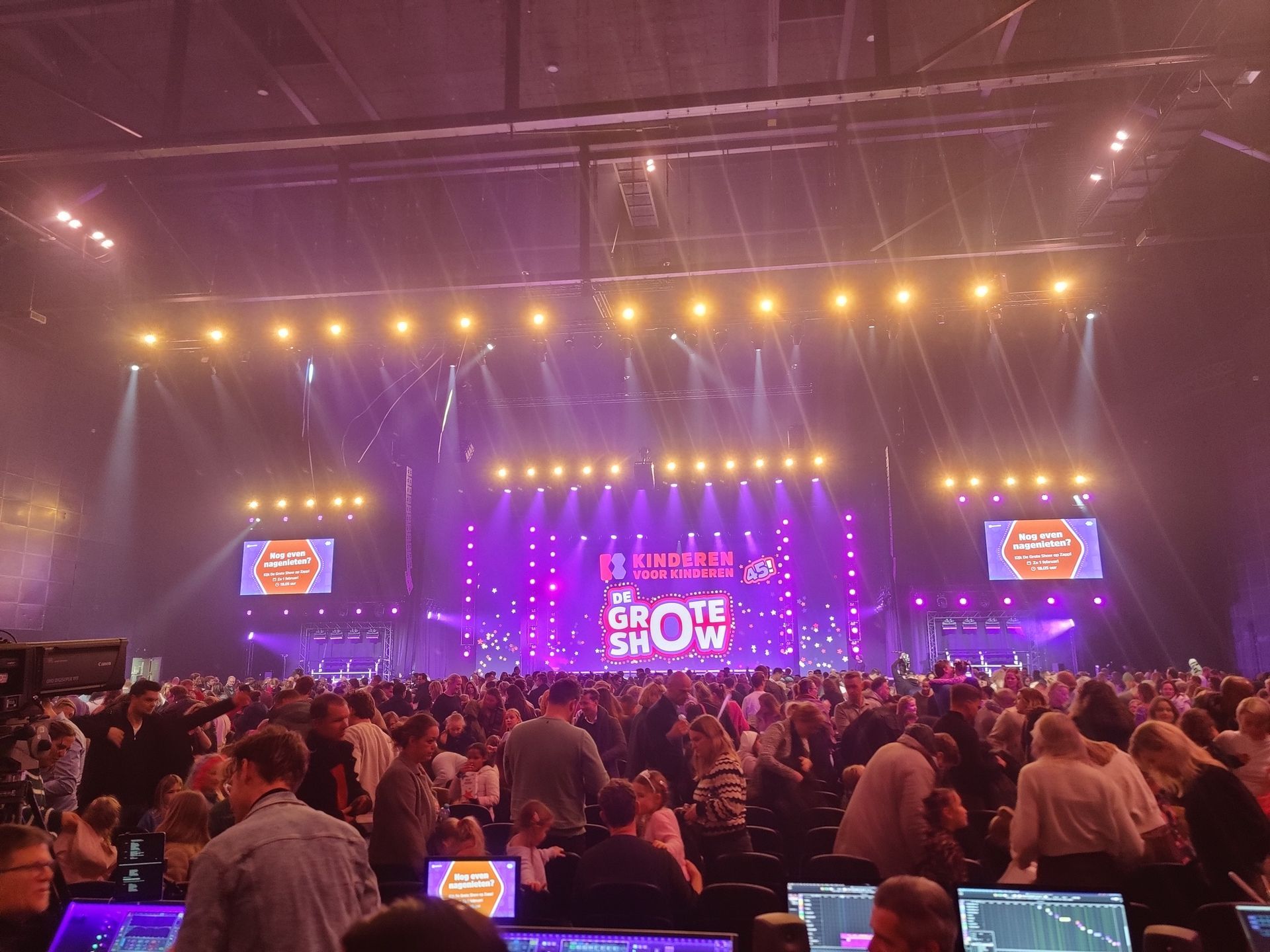 Een groep mensen zit voor een podium tijdens een concert.