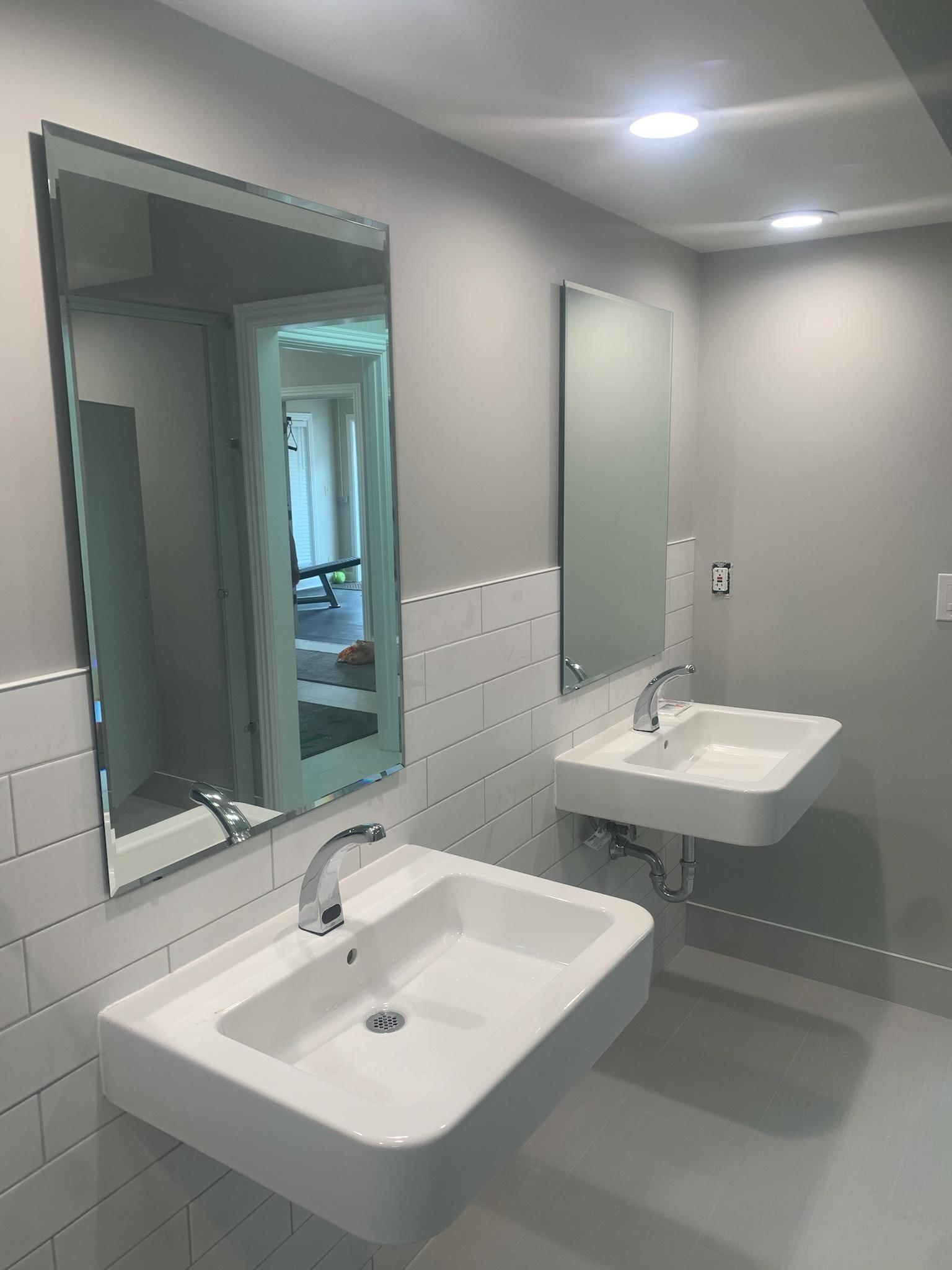 Two white sinks and mirrors in a modern, light-gray bathroom.
