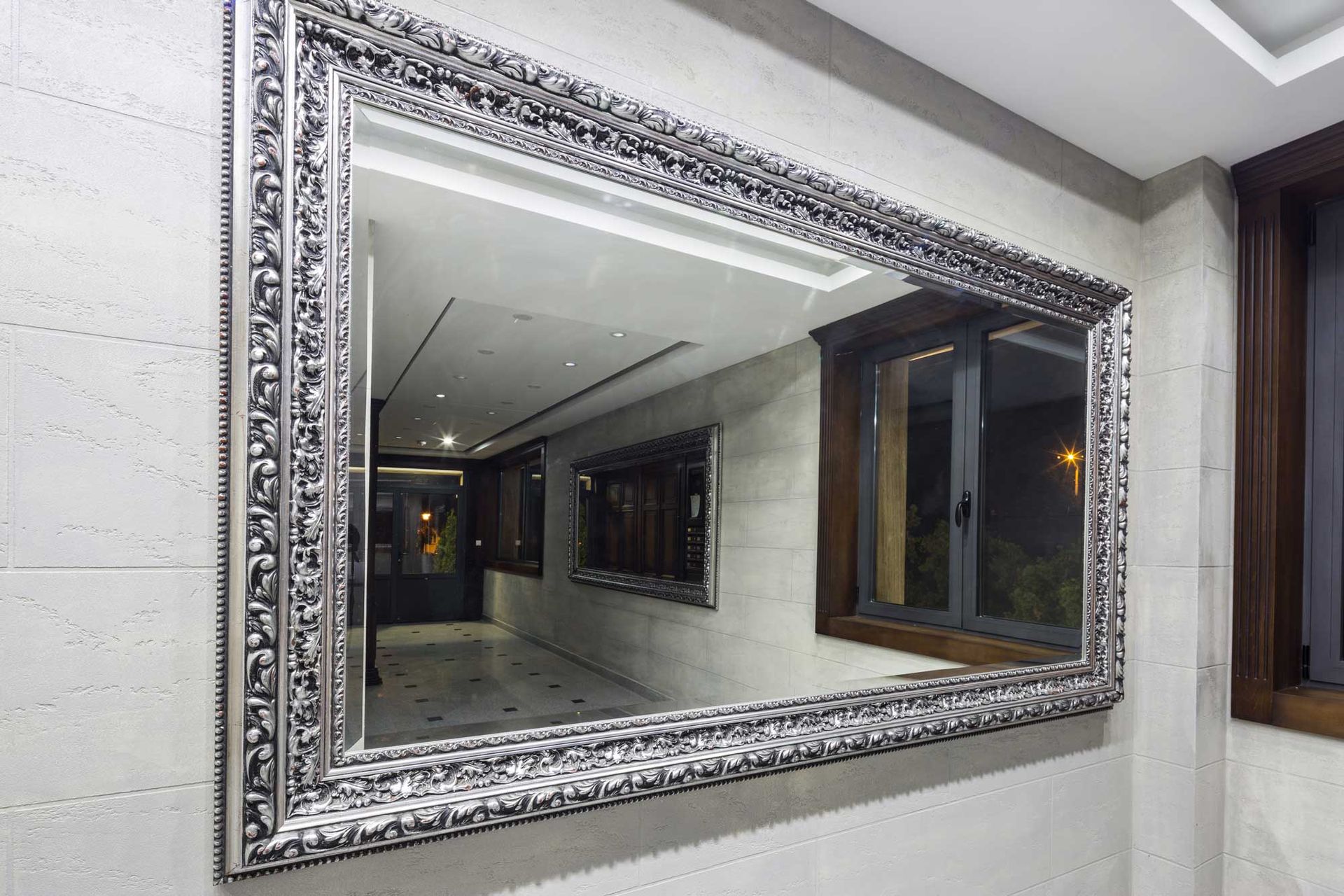 A large, ornate, silver-framed wall mirror showcases elegant mirrors for interior home decor. A large, ornate, silver-framed wall mirror showcases elegant mirrors for interior home decor.